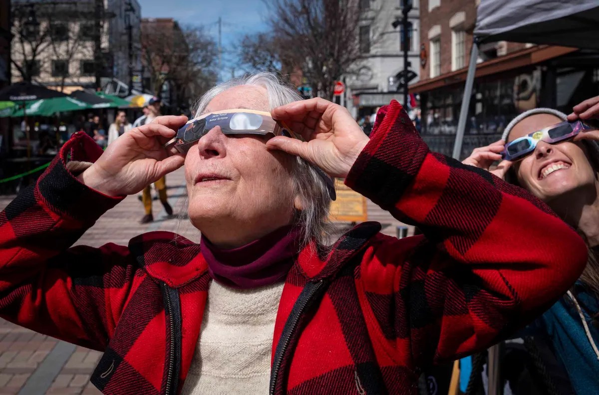 Two people wearing solar eclipse glasses looking up at the sky.