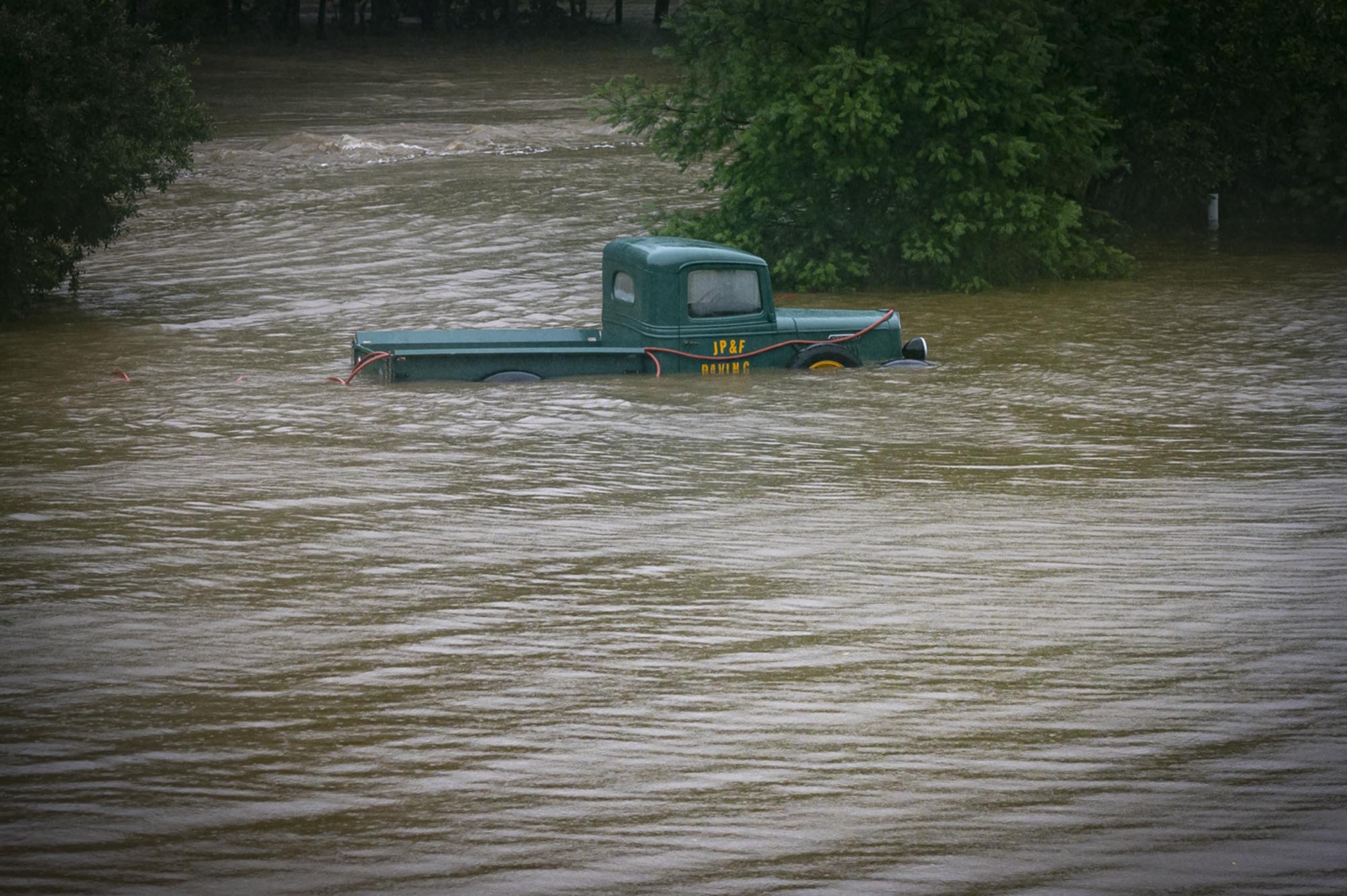 a green truck in a flooded river.