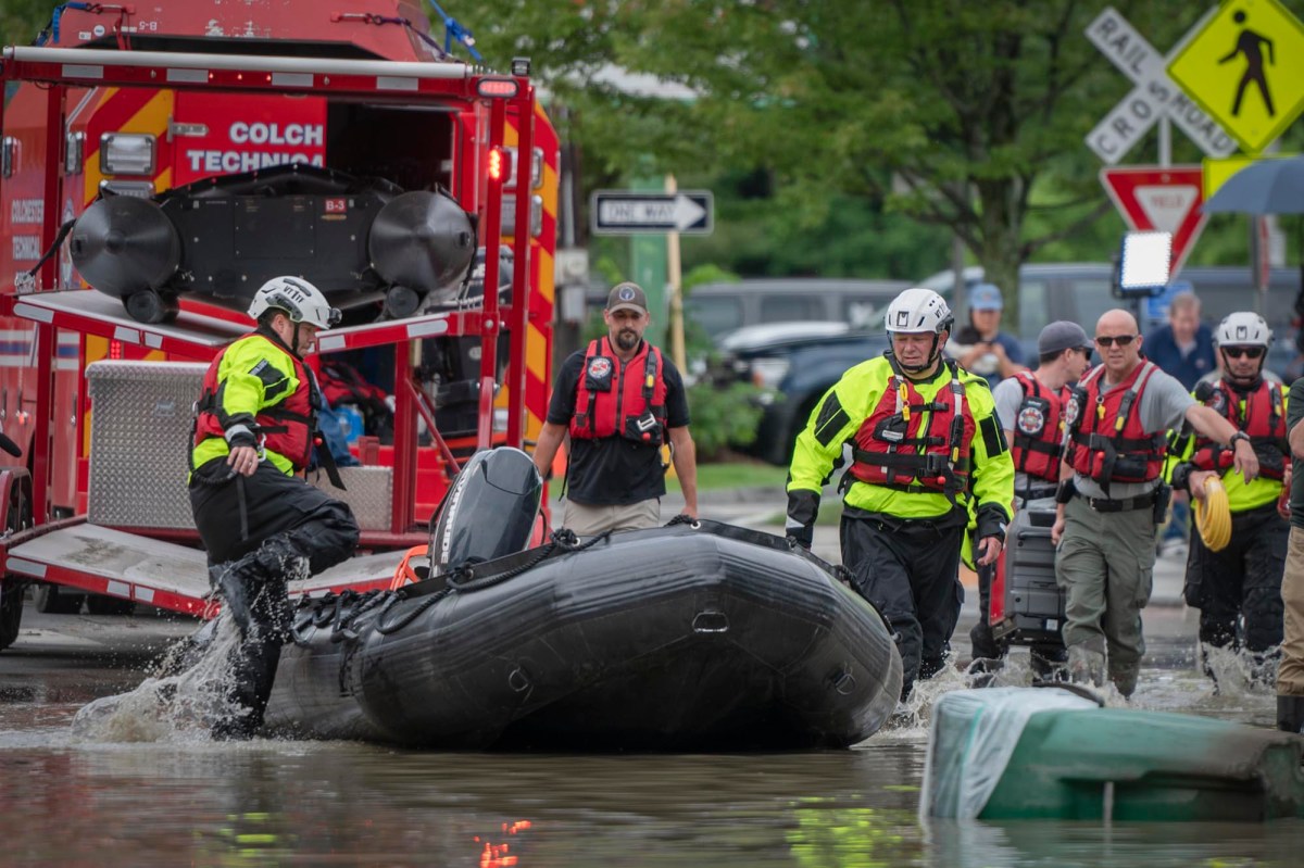 a group of people standing on a boat in a flooded street.