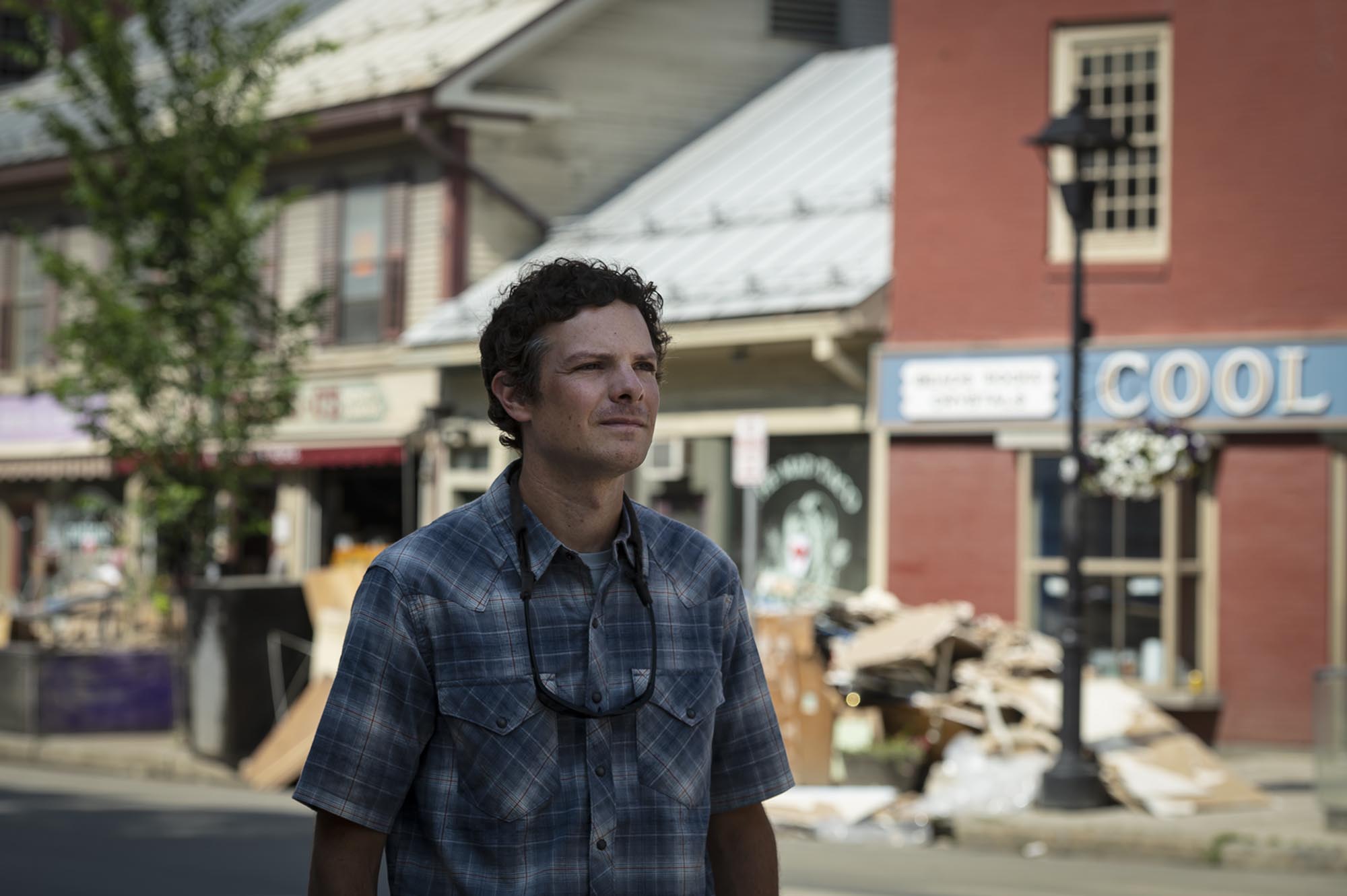 A man in a plaid shirt standing on a street.